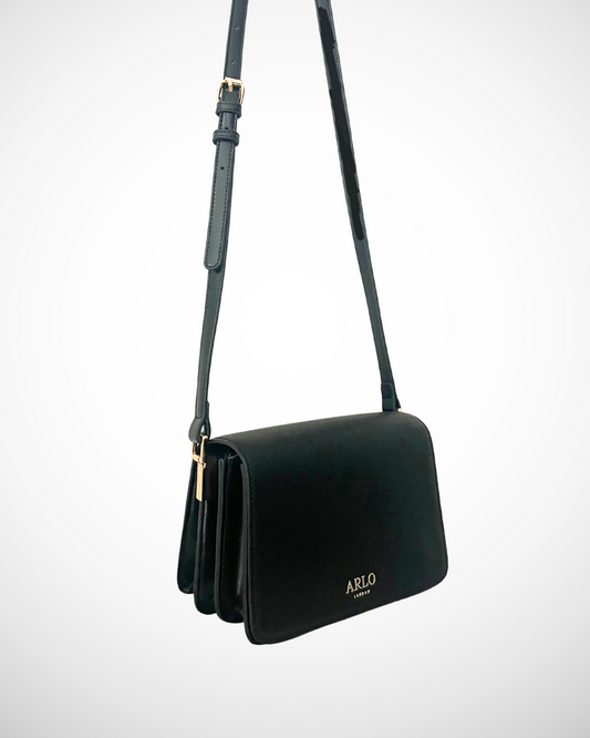 A black and gold vegan textured leather crossbody casual handbag for day use with adjustable strap. Minimal, quiet luxury, sophisticated, understated, simple design by ARLO London. Multiple organisation compartments with magnetic snap button closure.