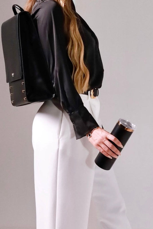 pretty professional woman with a smart black backpack for work holding a sophisticated black coffee travel flask that is insulated, wearing a smart office suit outfit. 
